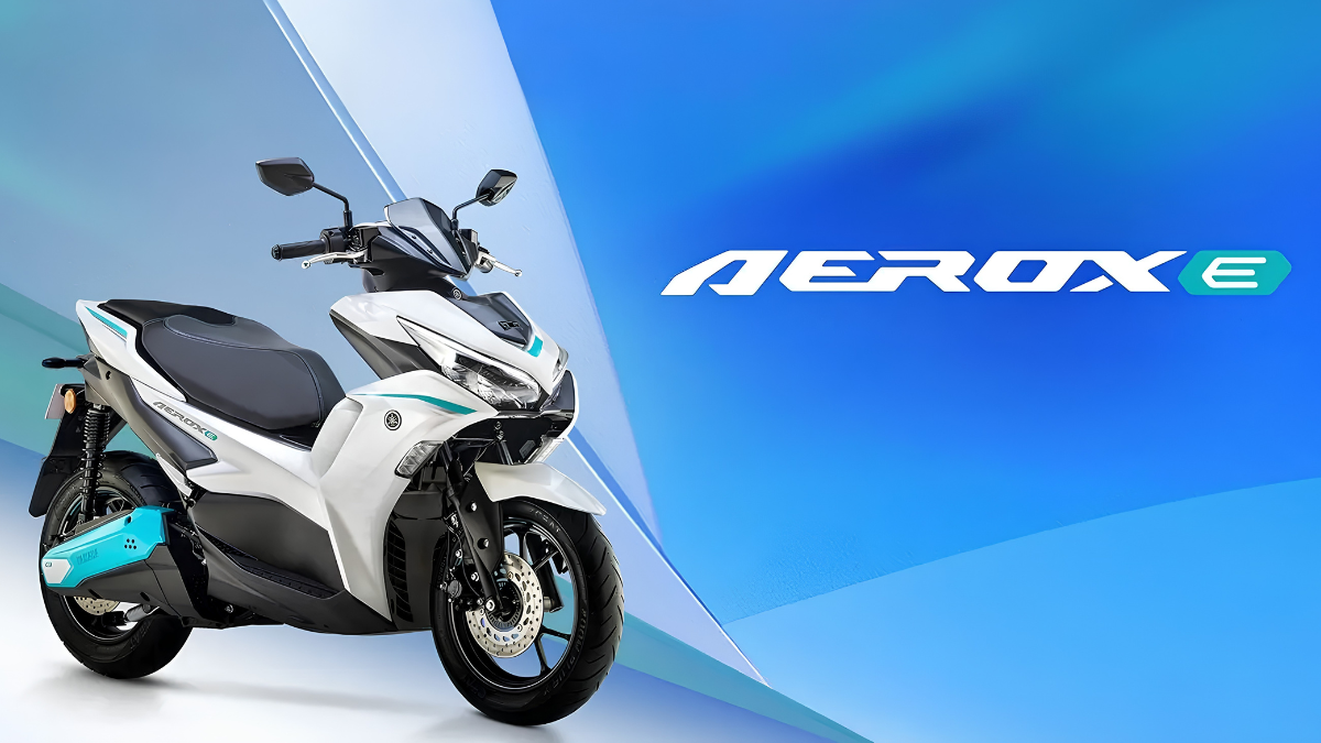 A white Yamaha Aerox-E scooter with cyan accents displayed on a blue studio background.