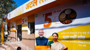 Entrance steps on left, orange and yellow Atal Canteen kiosk wall with thali graphic and two portraits facade.