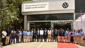 Staff in workwear and suits stand in front of the decorated Volkswagen Chhatrapati Sambhajinagar building exterior.