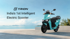 Black text overlay, teal blue E3 TRION electric scooter with headlights on, concrete ledge, open water, and blue sky.