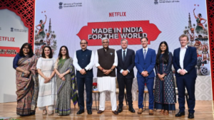Delegates in traditional and formal wear stand on stage before a screen for the As Seen on Netflix section launch.