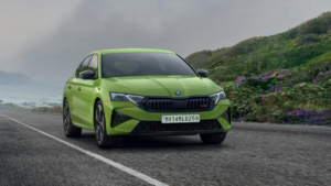 Green Škoda Octavia RS driving on coastal road with dark grille, led headlights, and green hills in background car.