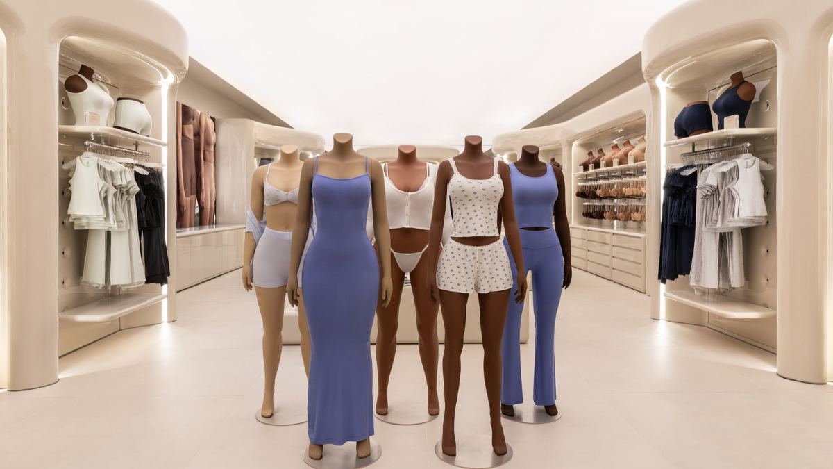 Mannequins displaying blue and white garments inside a cream-coloured showroom with shelving display.