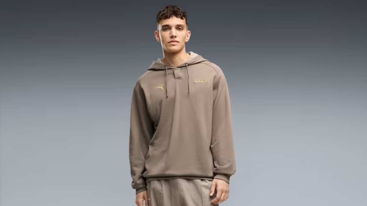 Heritage car interiors become everyday clothing from ₹4,499 1 Man standing in a light brown hooded sweatshirt against a gradient grey background studio.