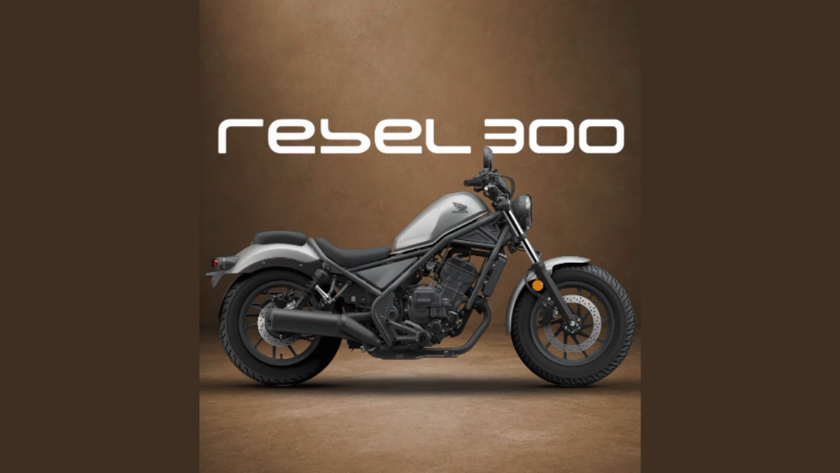 Rear wheel, low seat, silver fuel tank, engine, and front wheel on Honda Rebel 300 cruiser in studio setting.