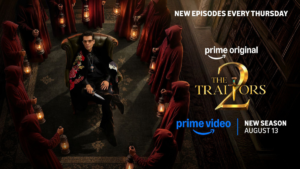 Red hooded figures with lanterns surrounding Karan Johar seated on a leather chair in a poster.