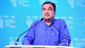 In the foreground, microphones sit before Nitin Gadkari speaking against a blue Global Fintech Fest backdrop for OneTag.