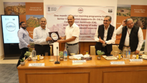 Men standing at a wooden table holding a plaque during the Induction Training Programme launch ceremony event
