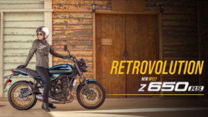 A rider stands beside a Kawasaki Z650RS on the left, with text reading RETROVOLUTION on a wooden door to the right.