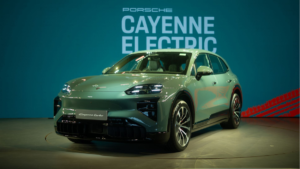 A green Porsche Cayenne Electric angles left in the foreground, backed by a teal wall with centered white text.