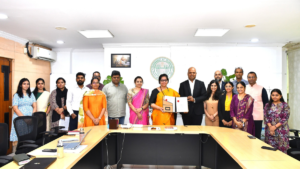 Officials around a wooden table holding a signed Suvidha document before a Government of Telangana wall emblem.